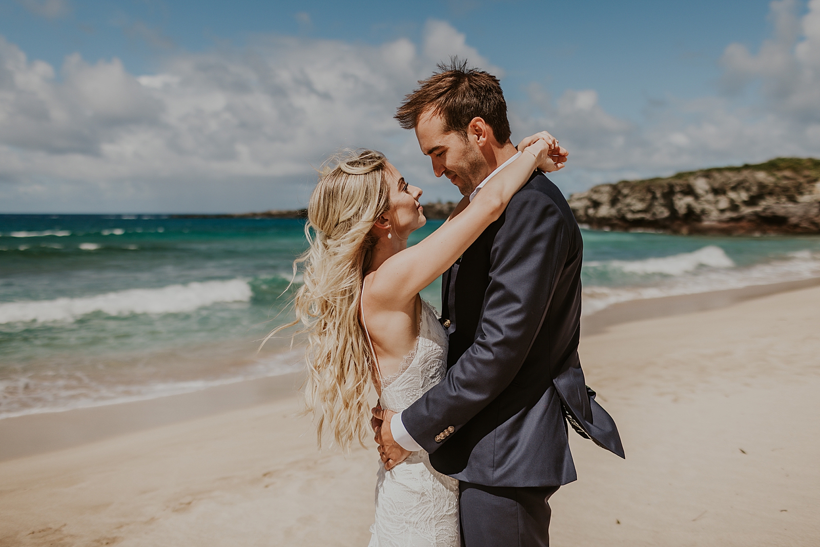 Bride and Groom with arms around each other in front of the blue clear ocean water