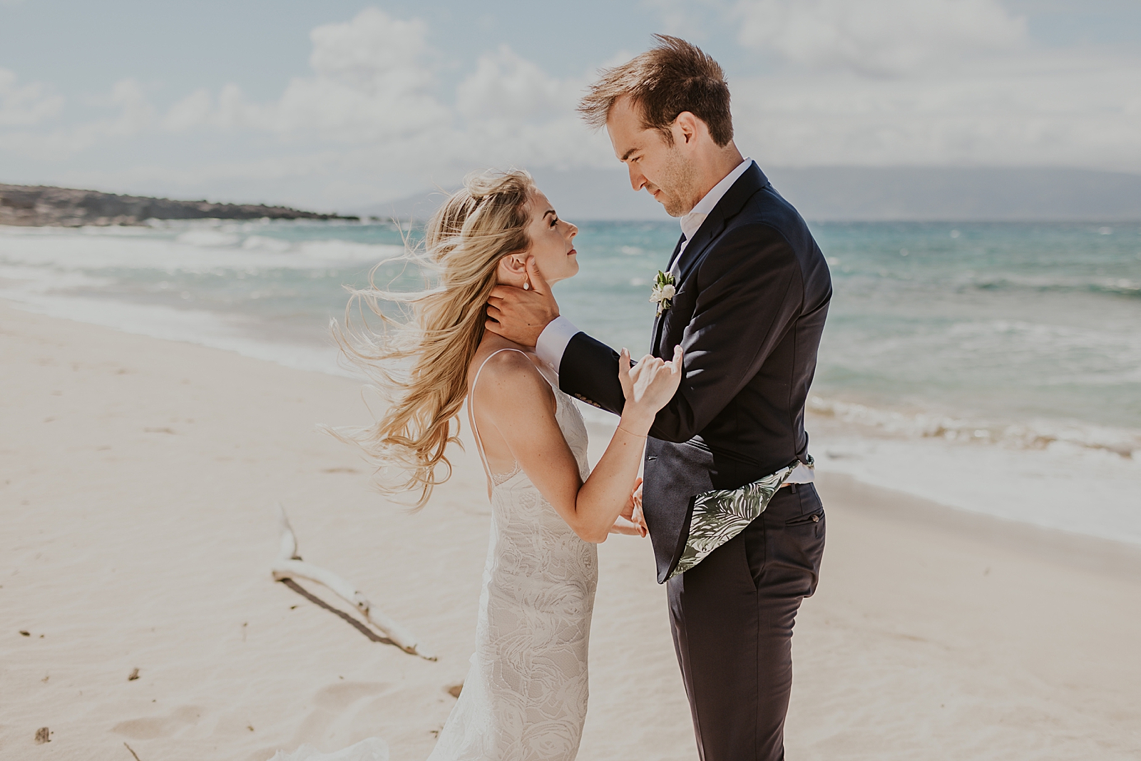 Bride and Groom holding each other and looking at each other on the beach in front of the ocean water